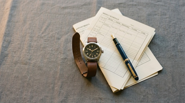 Relógio e planilha de horário sobre mesa, controle de jornada em ótica